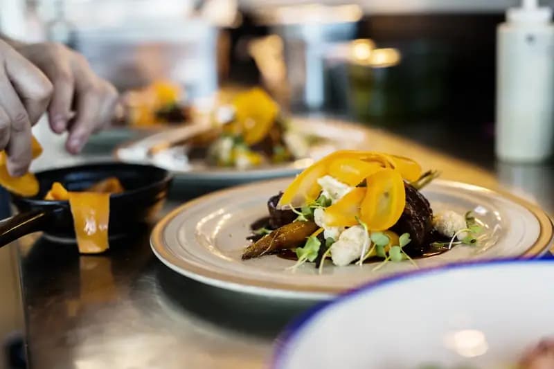 Chef cuisinier garnissant meticuleusement un plat gastronomique en cuisine